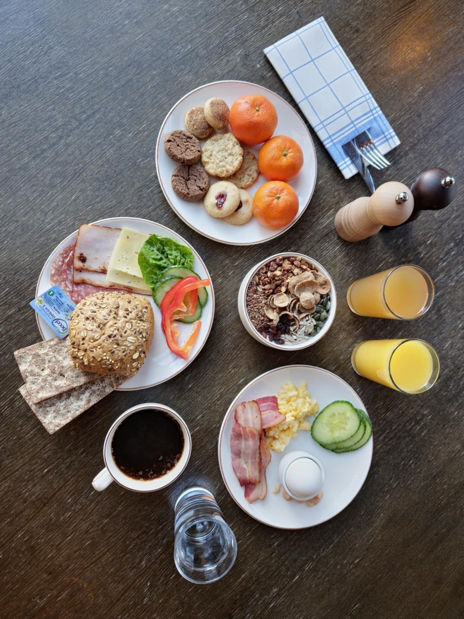 A breakfast spread with various foods and drinks on a wooden table.
