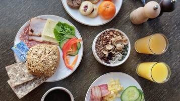 A breakfast spread with various foods and drinks on a wooden table.