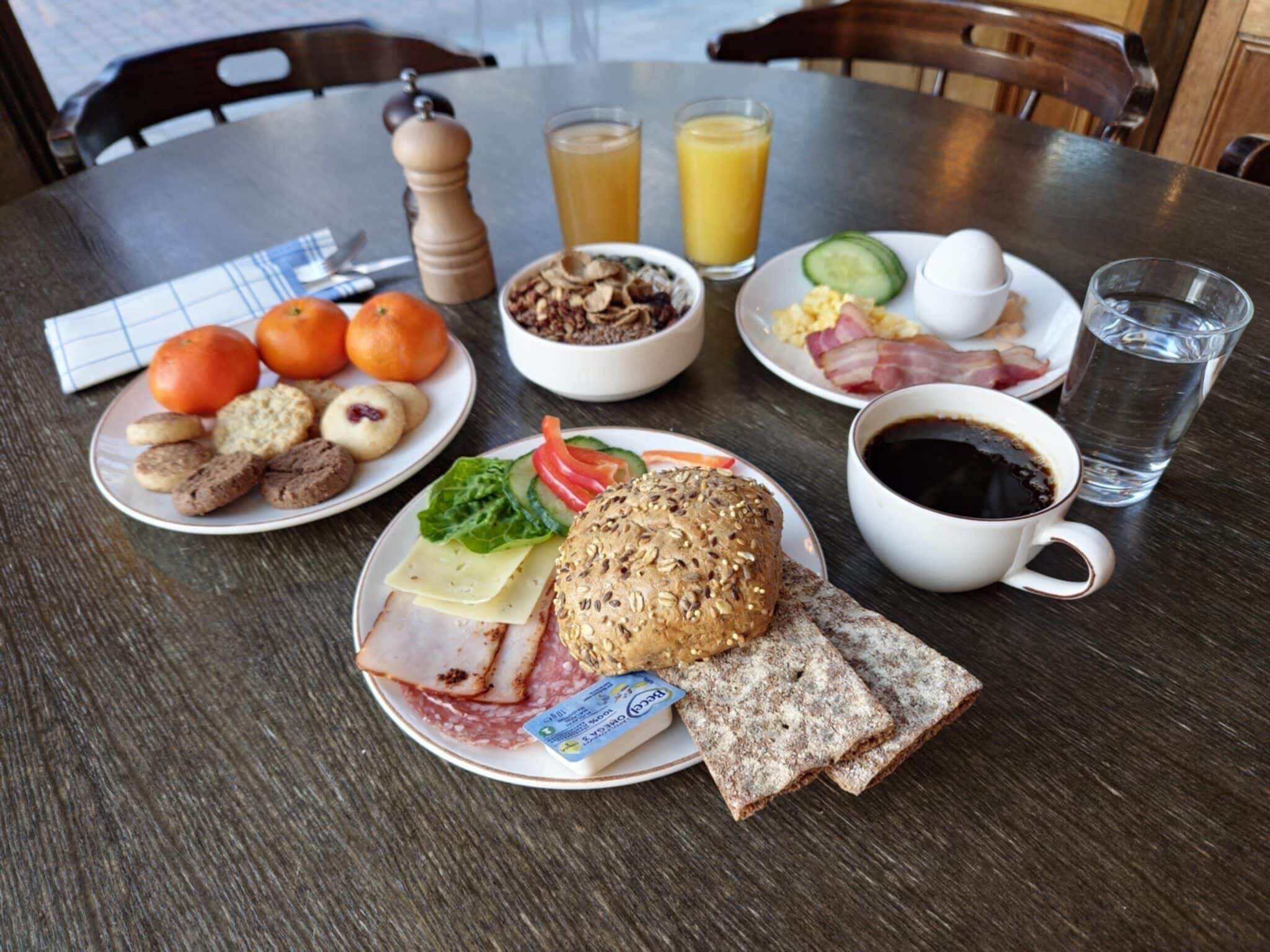 A breakfast table with plates of food, a coffee cup, and glasses of orange juice.