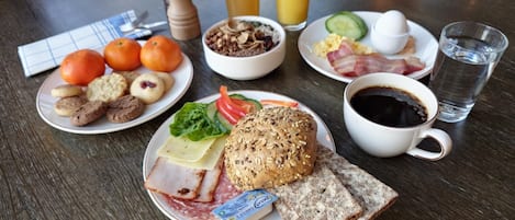 A breakfast table with plates of food, a coffee cup, and glasses of orange juice.