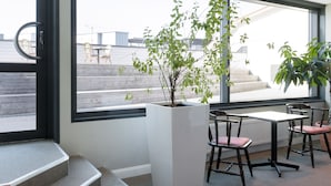 A modern office space with a large window, a potted plant, and a table with chairs.