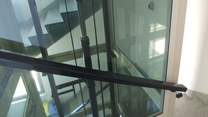 Un interior moderno con una escalera de cristal y barandillas de metal.