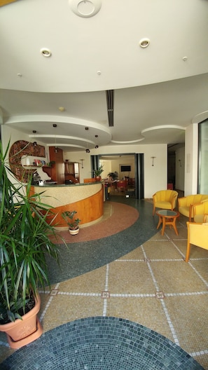 A hotel lobby with a reception desk, seating area, and a dining space. - Hotel La Perla (Roseto degli Abruzzi)