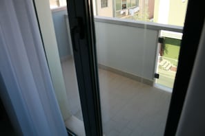 A view from inside a room to a balcony with a tiled floor and a railing. - Hotel La Perla (Roseto degli Abruzzi)