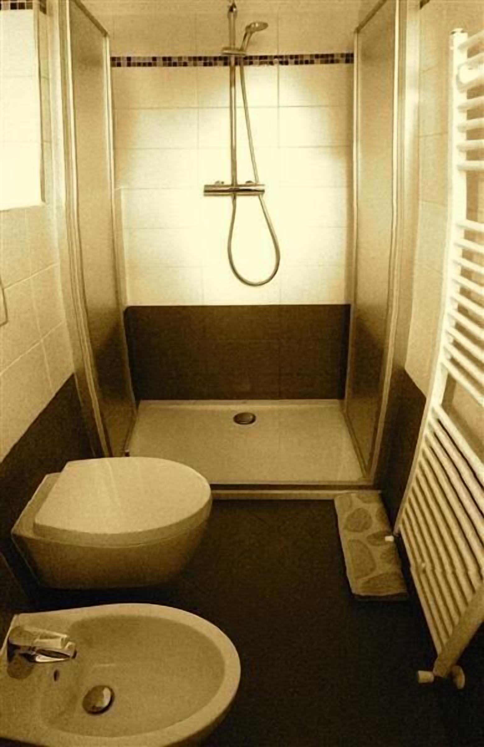 A small, enclosed bathroom with a toilet, sink, and shower.