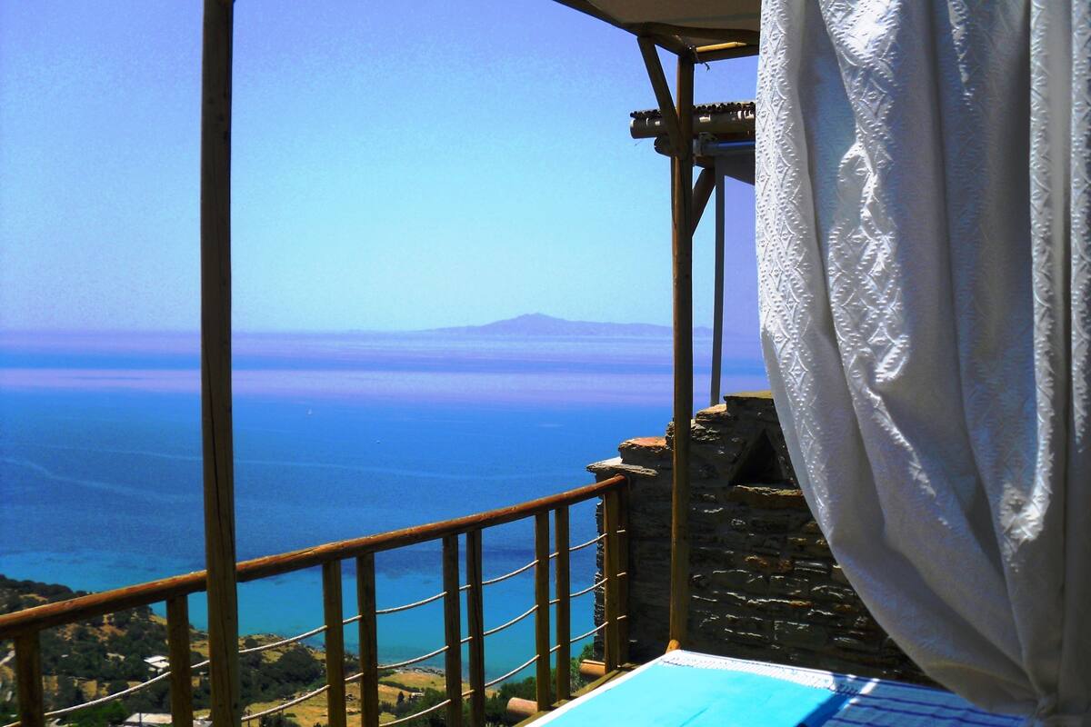 A balcony with a view of the sea and a mountain in the distance.
