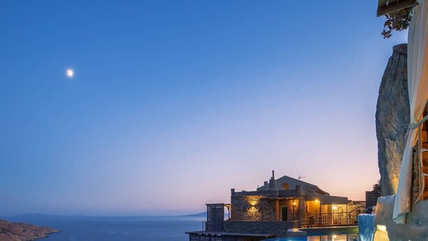 A infinity pool with a view of the sea and a building with stone architecture. - Aegean Castle  Andros - Adults Only (Andros)