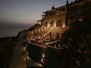 A stone building with outdoor dining, overlooking a body of water. - Aegean Castle  Andros - Adults Only (Andros)