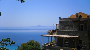A stone building with a balcony overlooking a clear blue sea and distant mountains. - Aegean Castle  Andros - Adults Only (Andros)