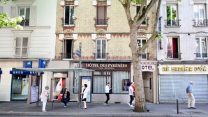La façade d’un hôtel, avec une enseigne indiquant « Hôtel des Pyrénées » et un volet fermé sur la droite.