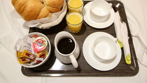 A tray with croissants, juice, coffee, and condiments. - Hôtel des Pyrénées (Paris)
