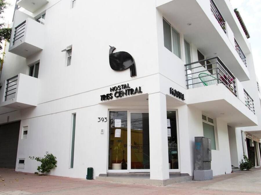 Un edifici modern amb un rètol que diu "HOSTAL TRIS CENTRAL" i un logotip d'un ocell negre.