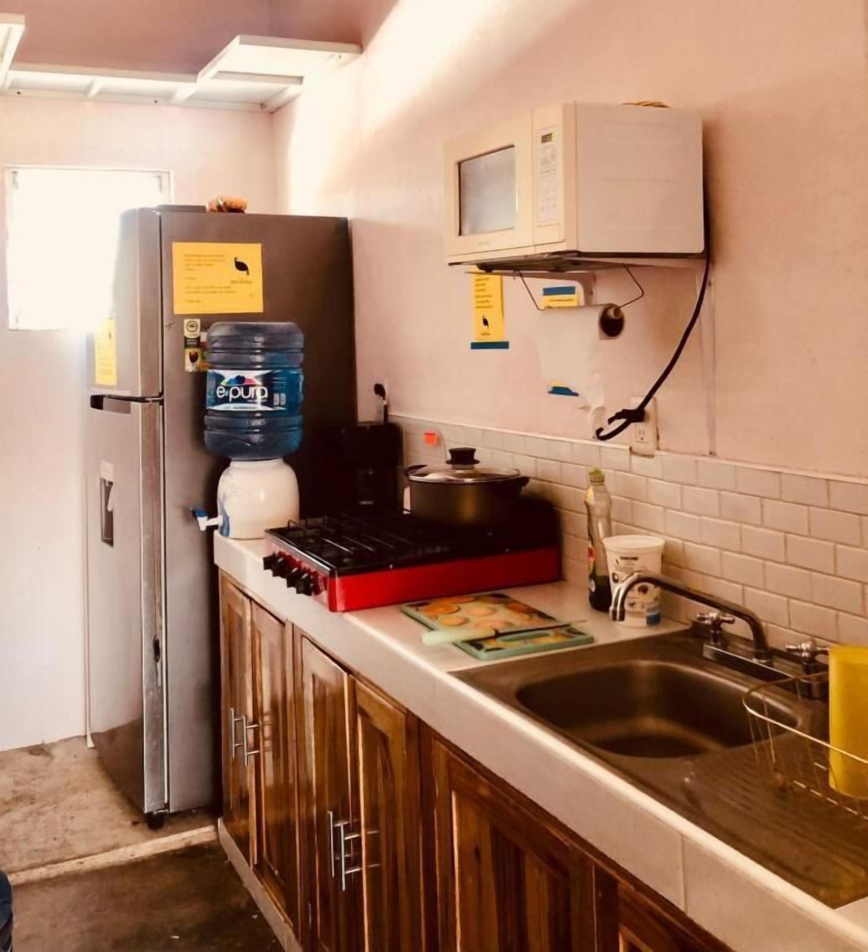 Een keuken met een koelkast, waterdispenser, fornuis, spoelbak en kastjes.