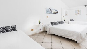 Ein schlicht eingerichtetes Hotelzimmer mit zwei Betten, einem kleinen Tisch und einem an der Wand hängenden Kunstwerk.
