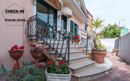 A hotel entrance with a check-in sign, a staircase, and potted plants.