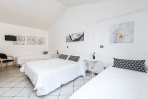 A hotel room with two beds, a chair, a small table, and artwork on the walls. - Hotel La Villetta (Fiumicino)