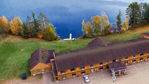 A motel with a long building, a parking lot, and a lake in the background.