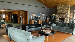 A spacious living room with a stone fireplace, leather sofas, and a coffee table.