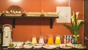 Um buffet de café da manhã com diversos alimentos, bebidas e um vaso de flores.