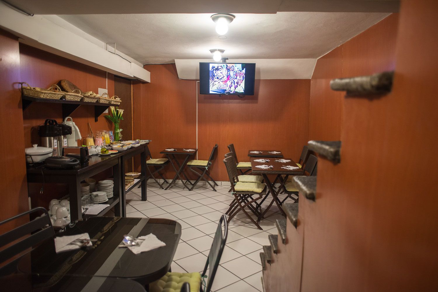 Un comedor compacto con una televisión montada en la pared, una mesa de buffet con diferentes platos y sillas plegables.