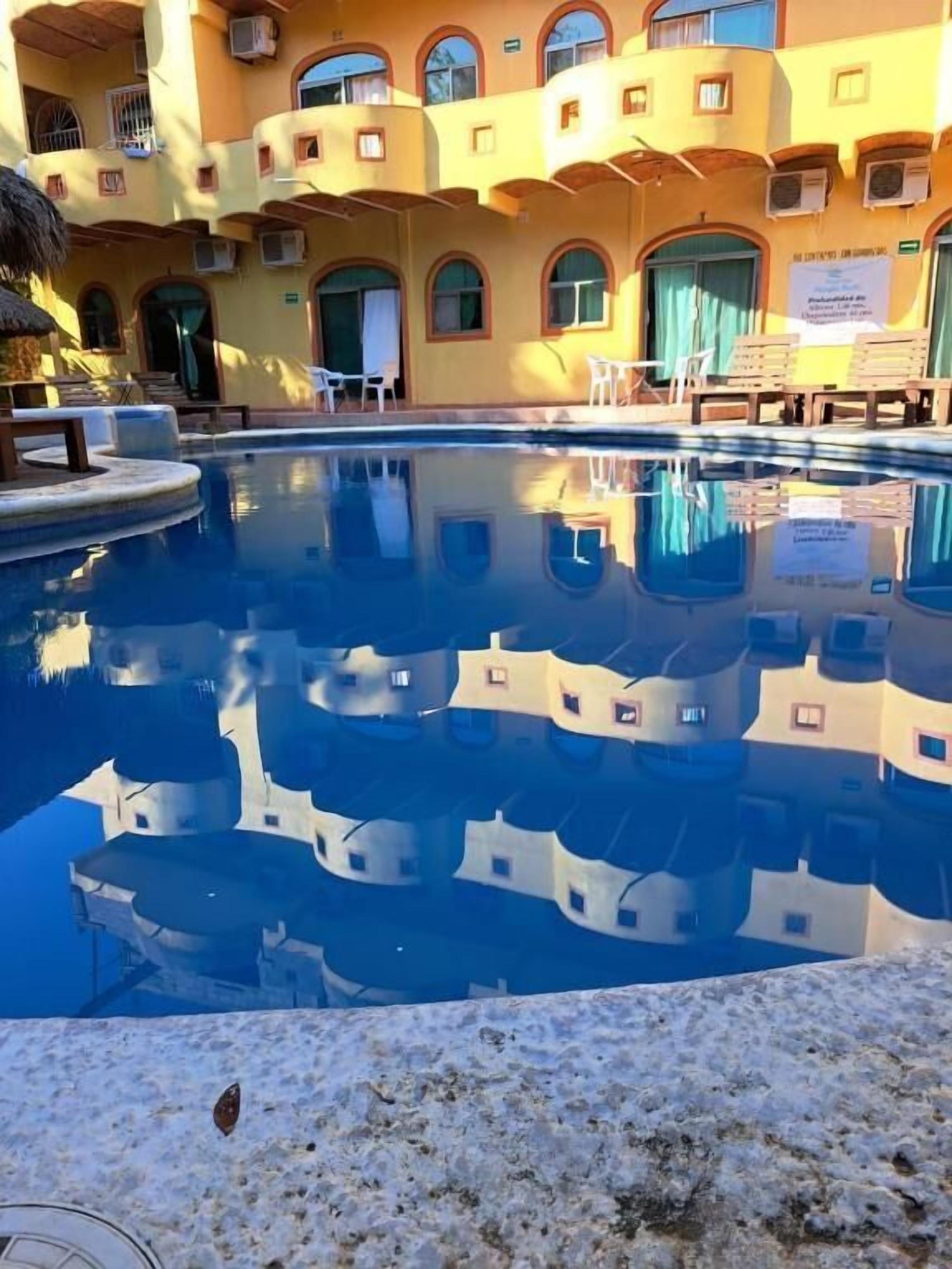 A swimming pool with a reflection of a building with arched windows and balconies.