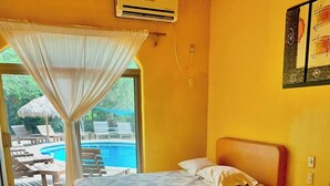 Una habitación con dos camas, una ventana que da a una piscina y un aire acondicionado.