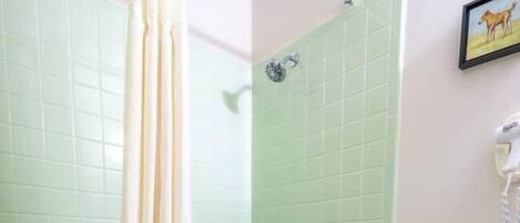A bathroom with a green bathtub, a white toilet, and a shower curtain.