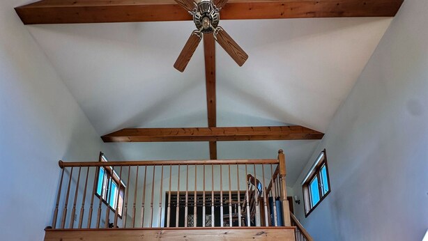 A spacious living area with a high ceiling, a wooden staircase, and a built-in kitchen visible through an open door. - Brittany Motel (Manchester Center)