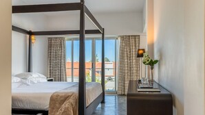 Una cama con dosel en una habitación de hotel con vistas a la ciudad a través de amplios ventanales.