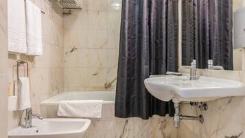 A bathroom with a bathtub, two sinks, a mirror, and a shower curtain.