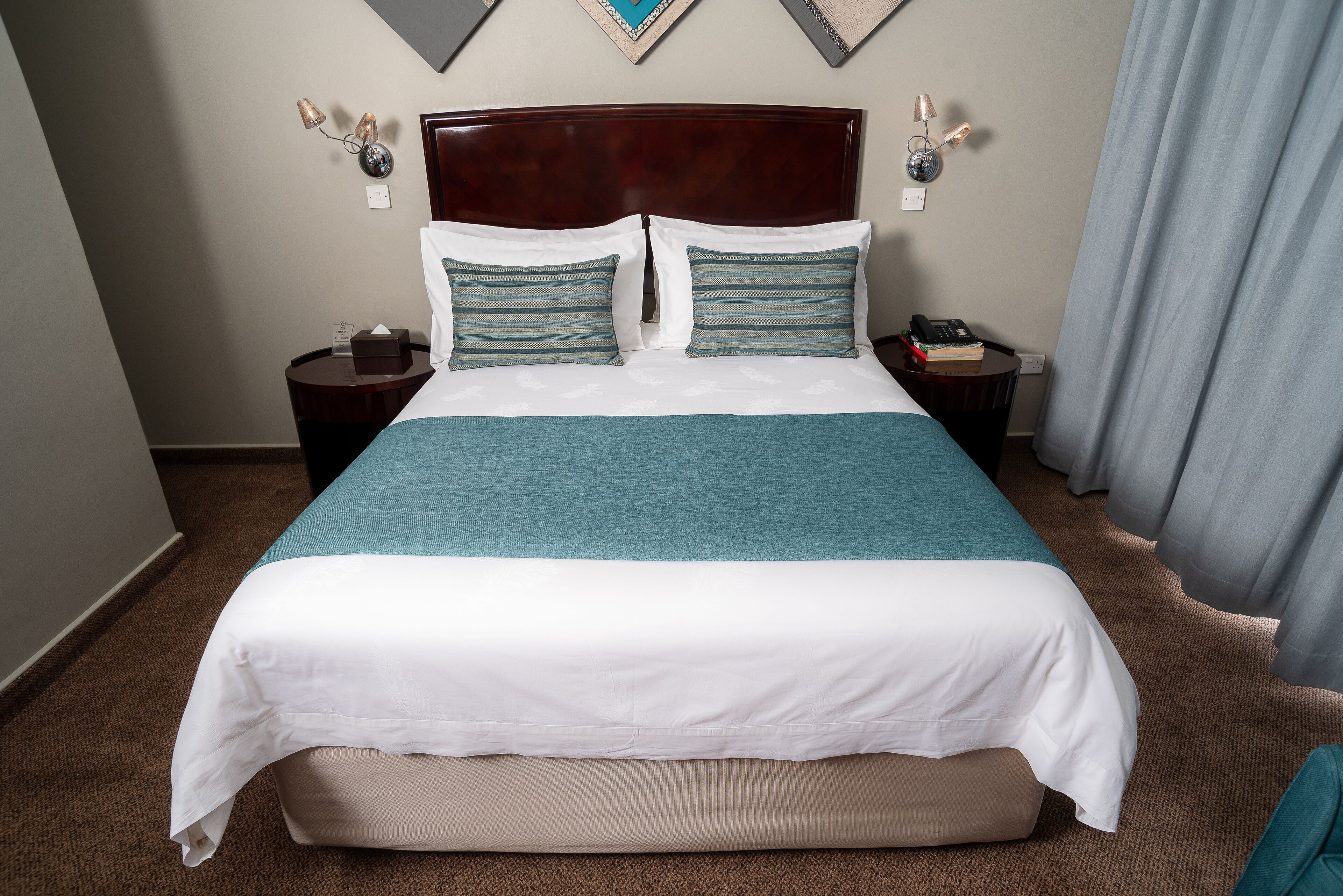 Una habitación de hotel con una cama grande, dos mesitas de noche y un cabecero.