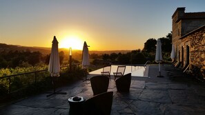 A sunset view from a terrace with stone flooring, outdoor seating, and umbrellas. - Casa Valxisto Country House (Penafiel)