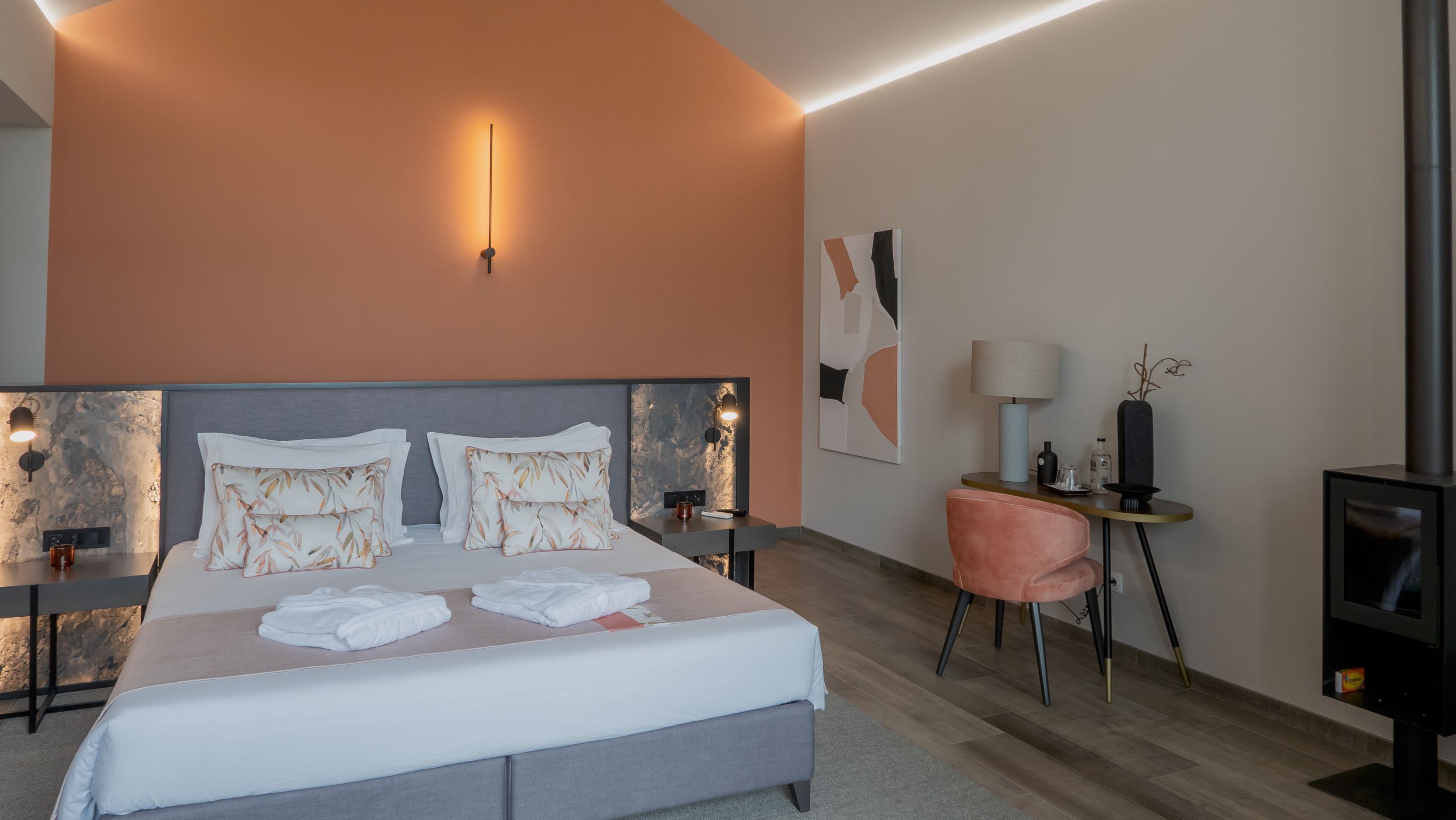 Una habitación de hotel moderna con una cama grande, un escritorio con lámpara, una silla y una chimenea.