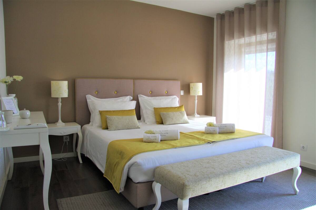 Ein Hotelzimmer mit einem großen Bett, zwei Nachttischen, einem Schreibtisch und einer Bank.