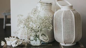 A rustic table with a vintage lantern, a metal milk jug, and a glass vase with white flowers.