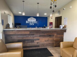 A reception desk with a blue wall and a logo, wooden paneling, and two leather chairs.
