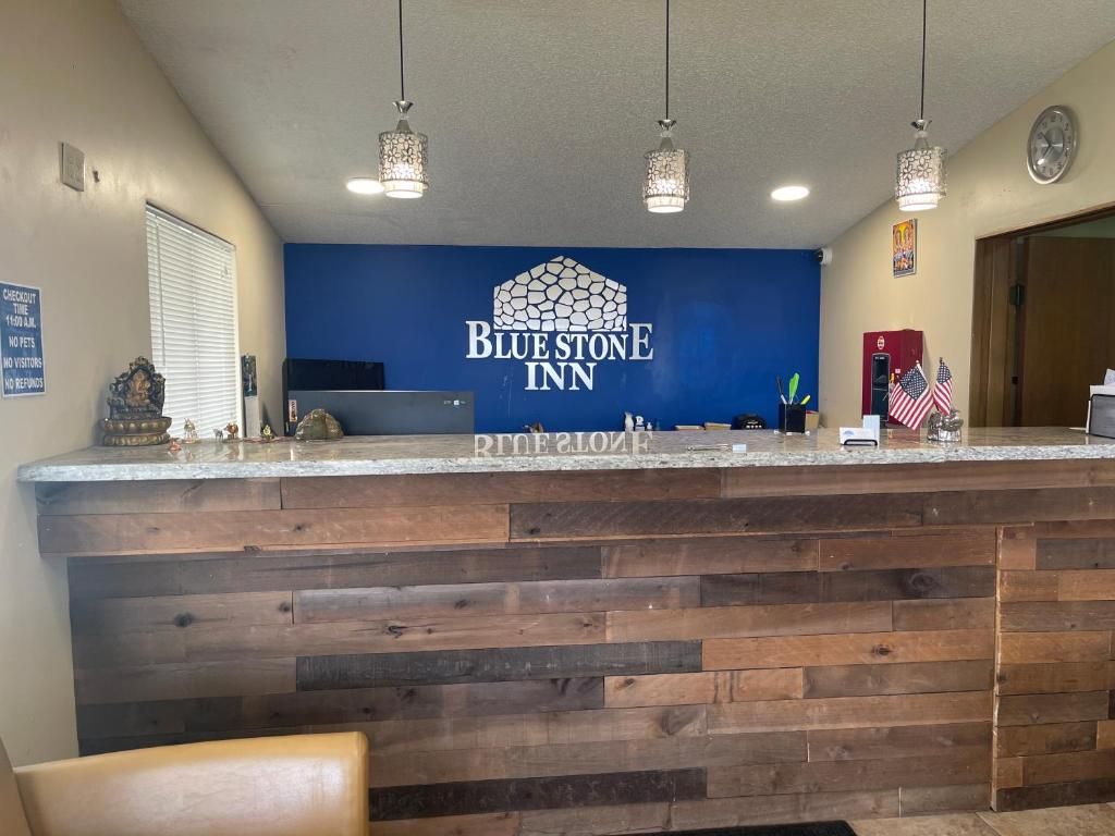 A reception area with a Blue Stone Inn sign, a wooden counter, and a clock on the wall.