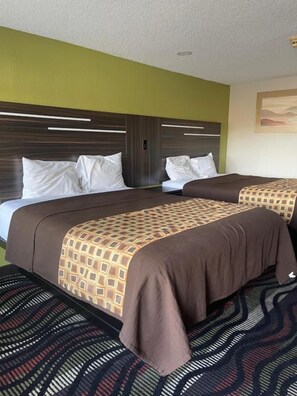 A hotel room with two beds, a patterned carpet, and a modern headboard.