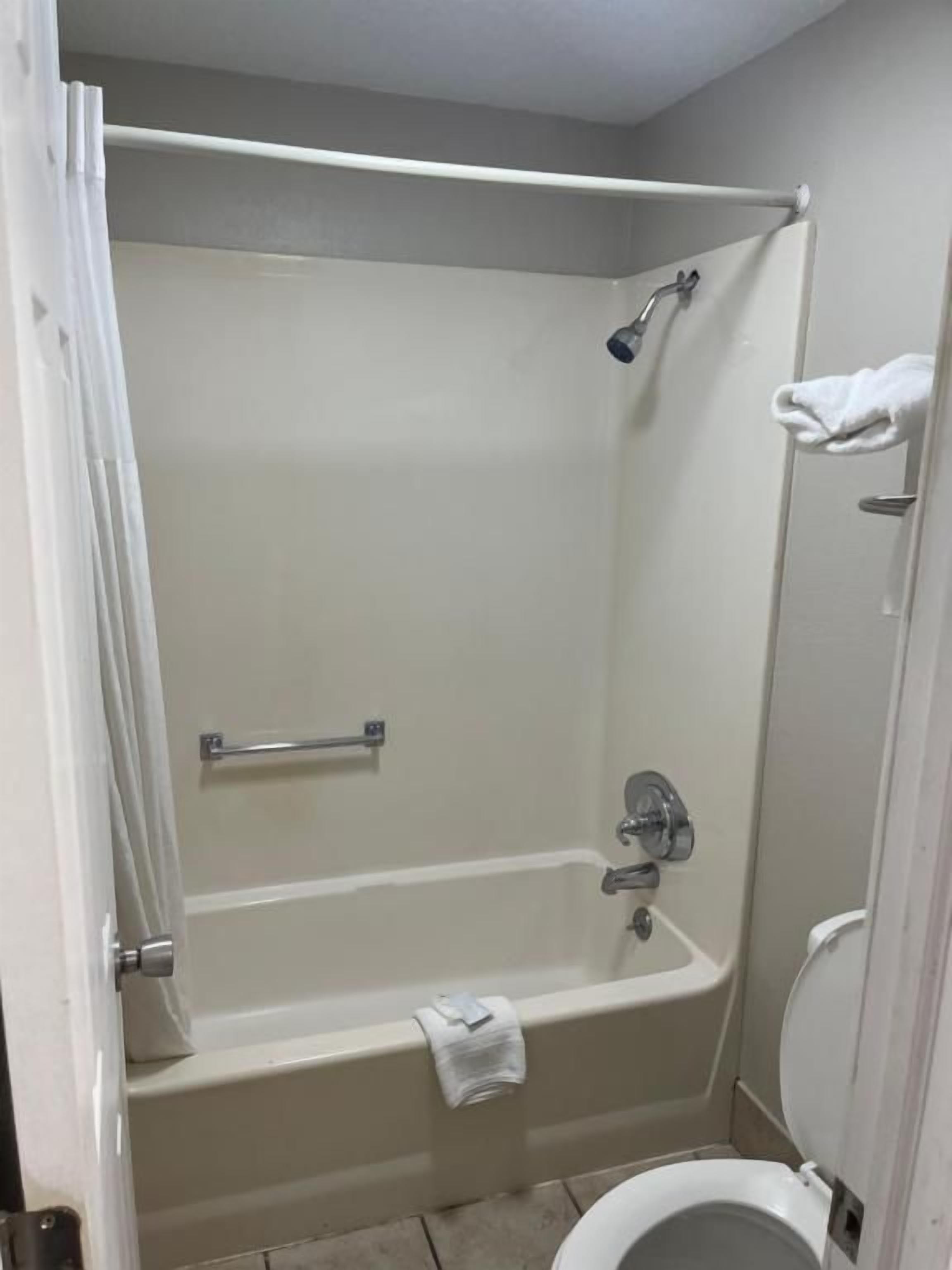A bathroom with a bathtub, a toilet, and a shower area.