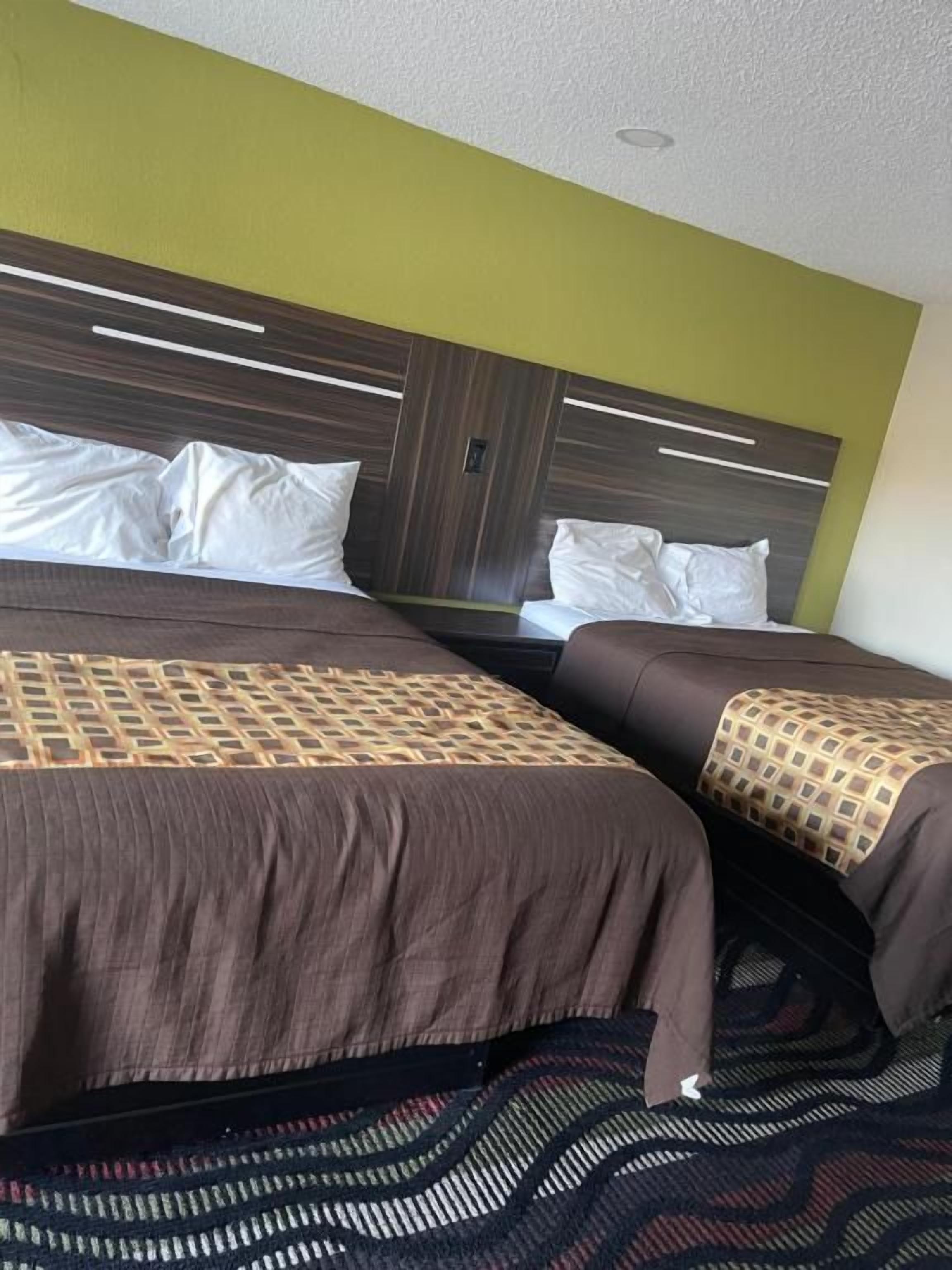 Habitación de hotel con dos camas, una colcha estampada y un cabecero con líneas horizontales.