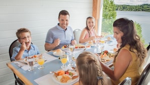 A family dining at a table with a view of a lake. - Ermitage Saint-Antoine (Lac-Bouchette)
