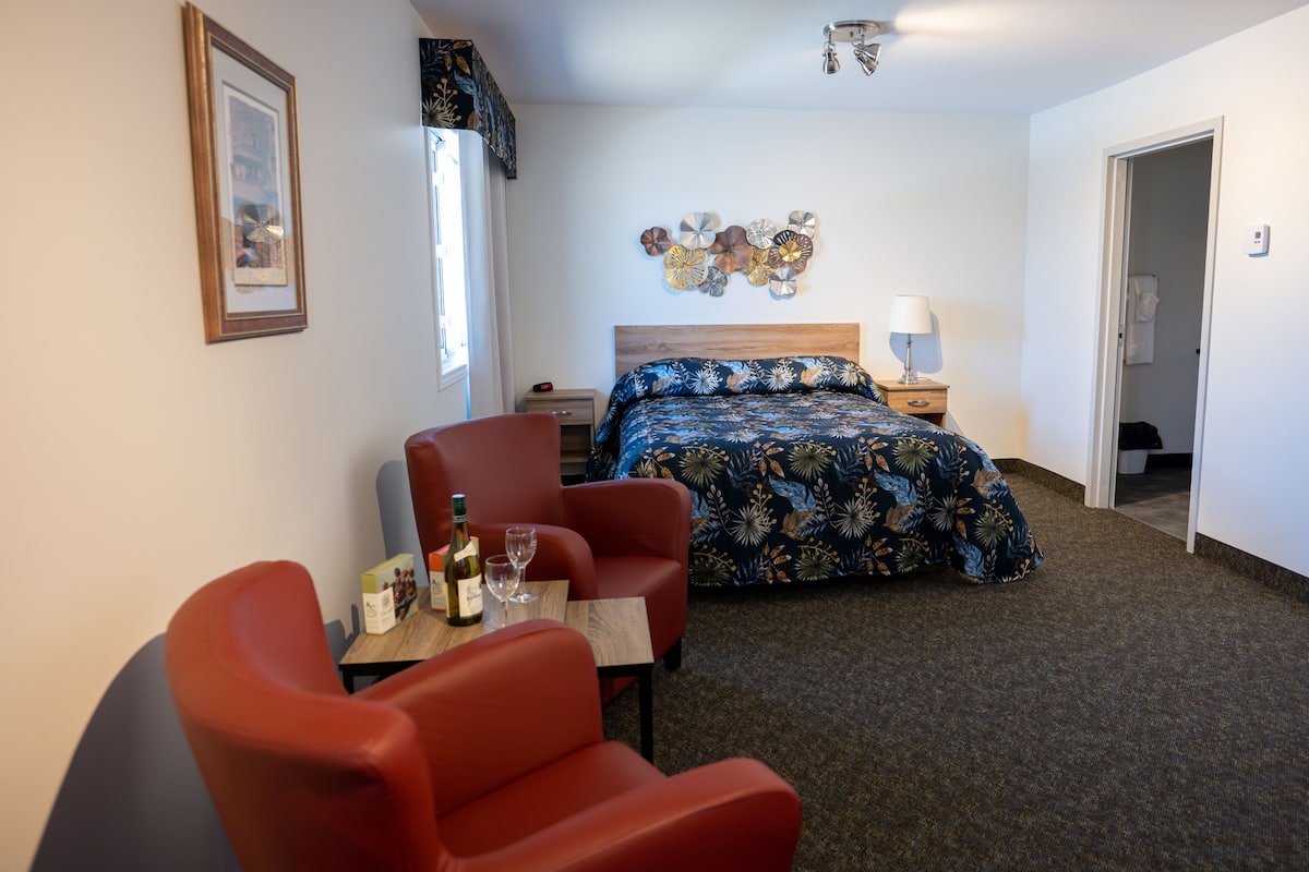 A bedroom with a bed, a desk with a chair, a nightstand, and a wall with decorative plates.