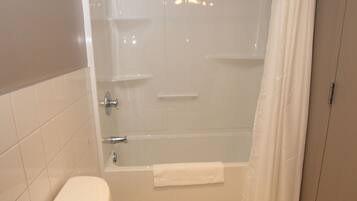 A bathroom with a toilet, bathtub, and shower curtain.