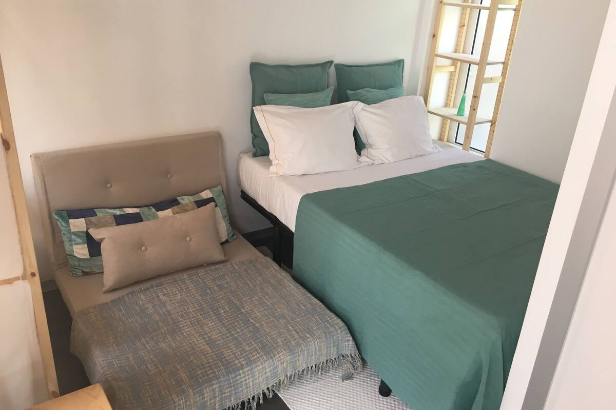 A bedroom with a bed, a bench, and a window.