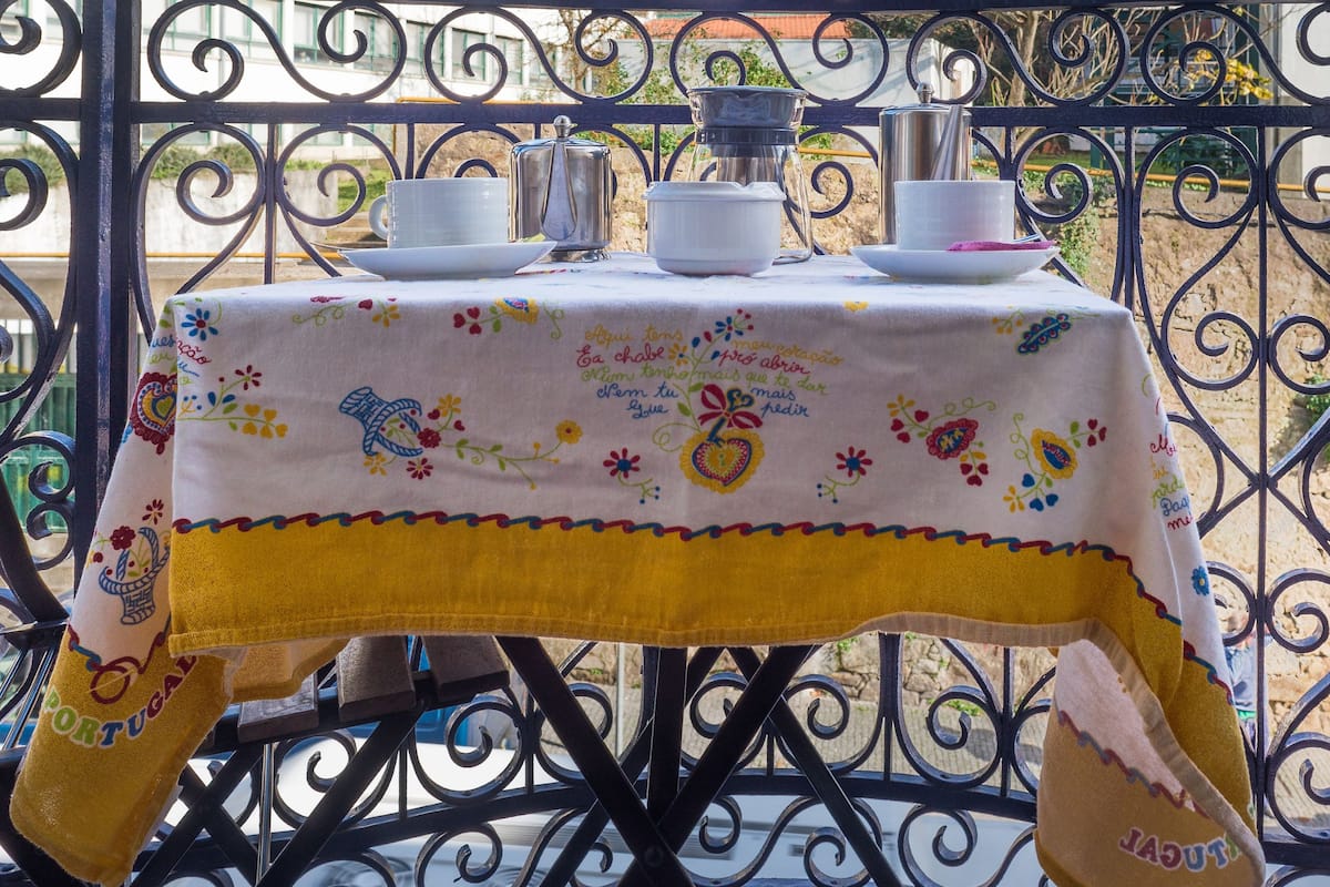 A table set outdoors with a tablecloth, plates, cups, and a pitcher.