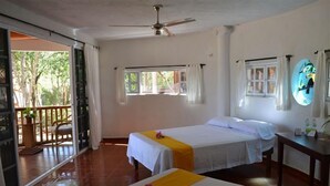 Quarto com duas camas, ventilador de teto, janela com cortinas e vista para o exterior.