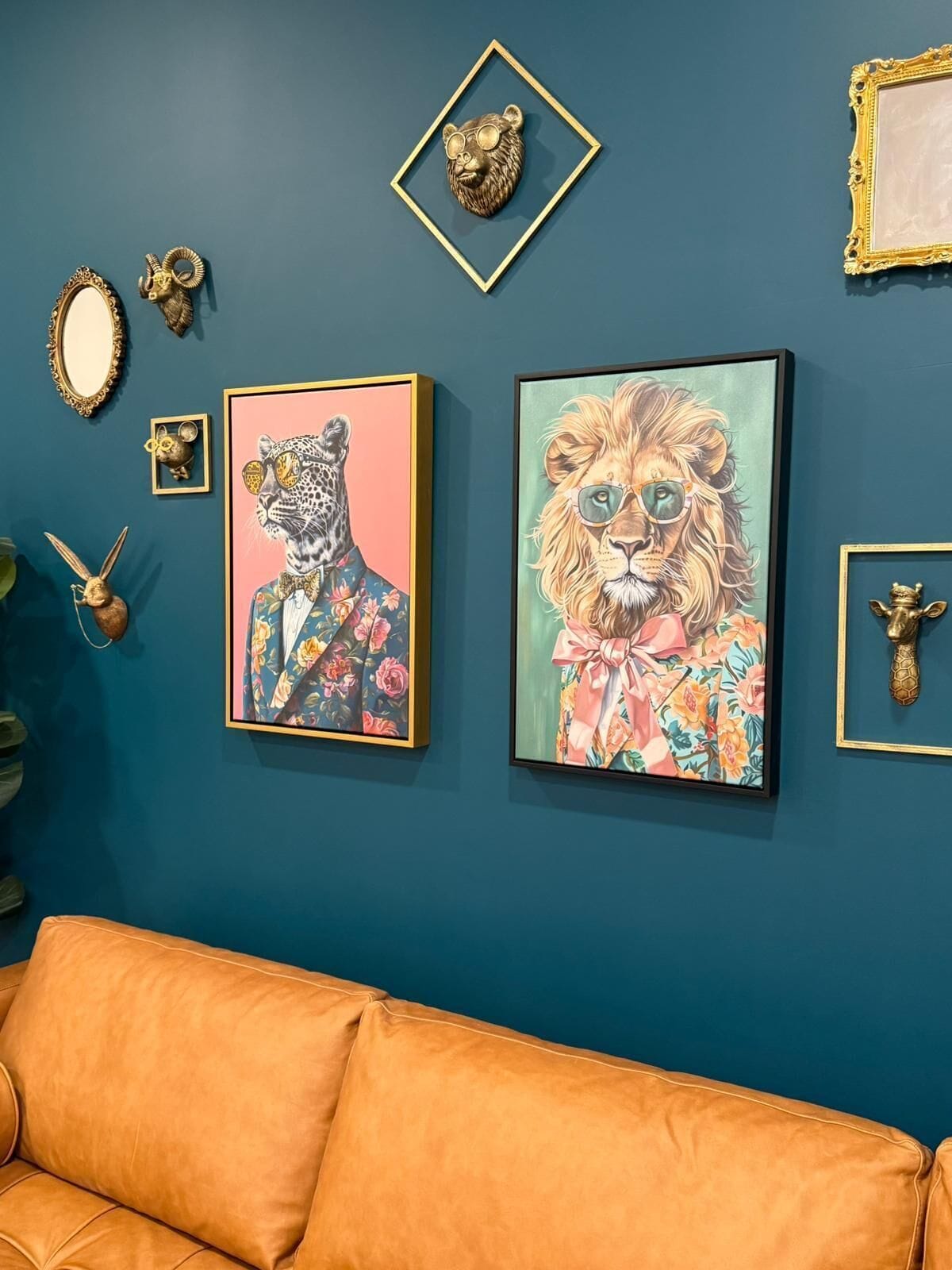 A room with a blue wall, two framed animal portraits, a mirror, and a small decorative item.