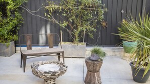 A patio with a rustic wooden chair, a woven basket, and potted plants against a dark wall. - 1906 Mission (San Francisco)