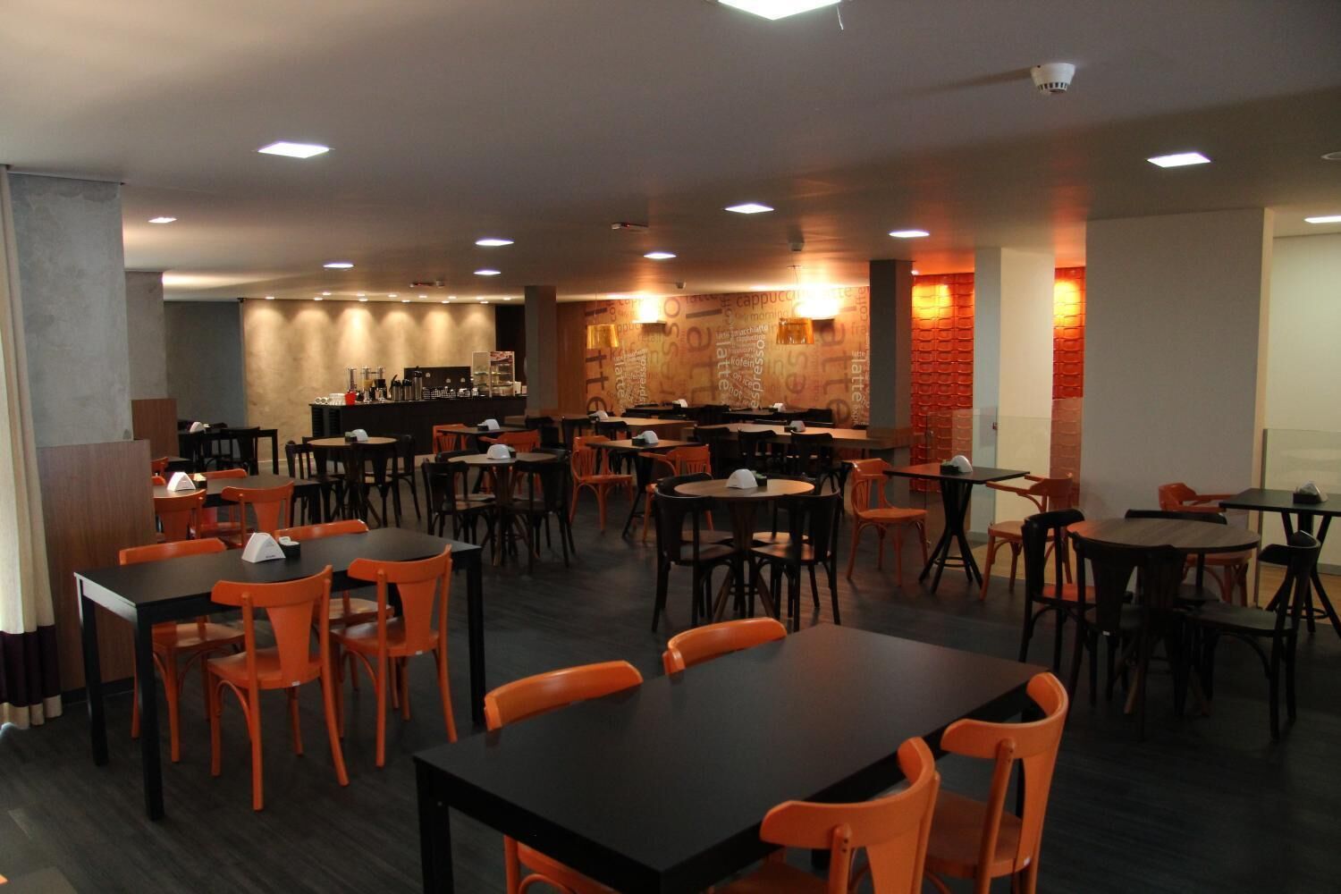 Un restaurante con varias mesas y sillas, una zona de bar y una pared de ladrillo.