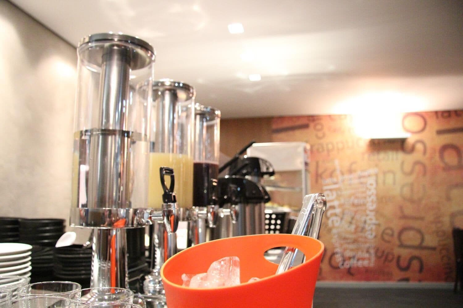 A bar area with multiple dispensers and a coffee machine, with a wall featuring the word "espresso" prominently.